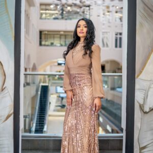 Turn heads in this breathtaking champagne gown... Featuring a delicately pleated chiffon bodice with sheer balloon sleeves and a shimmering, sequin-embellished skirt that cascades with radiant detail, this piece is the epitome of timeless glamour. Perfect for evening galas, red-carpet moments, or upscale events where luxury is a must.