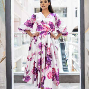 Violet Bloom Floral Midi Dress A celebration of timeless femininity, the Violet Bloom dress is a vision of soft elegance. Crafted from luxurious satin with a painterly floral print, it features a wrap-style bodice, voluminous puff sleeves, and a gracefully flared skirt that moves beautifully with every step. The vibrant hues of orchid, lilac, and fuchsia bloom across a pure ivory base, creating a fresh and romantic aesthetic.Perfect for garden parties, daytime soirées, or elevated occasions. The silhouette flatters every figure while maintaining a refined, effortless flow.