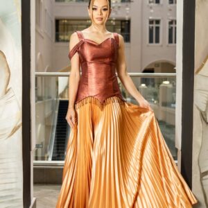 This couture‑inspired gown blends a sculpted, bronze sequined corset with an opulent, floor‑length gold pleated skirt creating a silhouette that’s equal parts dramatic and elegant. The structured bodice cinches at the waist and supports a graceful neckline, while the metallic pleats cascade in soft, rippling folds, catching light from every angle. Designed for special evenings where every detail matters, it strikes the ideal balance between artful structure and fluid movement.Pair with minimal jewelry, a sleek clutch, and neutral heels to let the gown’s metallic tones shine. Available in limited pieces.